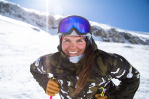 woman in ski gear standing on snowy ground smiling