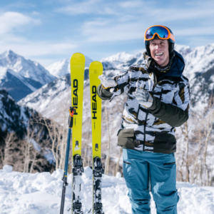 Man on snow standing next to upright skis