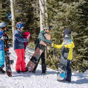 4 snowboarders in a group greeting each other