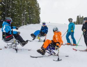 group of sliders and riders in regular and adaptive equipment talking in a circle