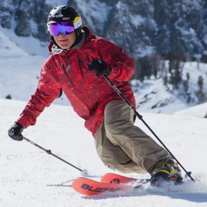 Man in red coat telemark skiing down snowy hill