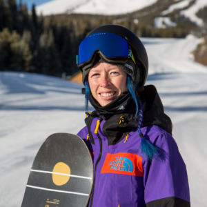 female snowboarder on snowy hill holding a snowboard