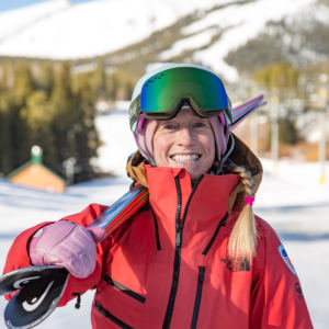 woman smiling holding skis on shoulder