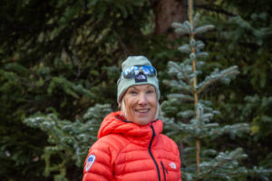 woman in red puffy jacket smiling at camera with alpine background
