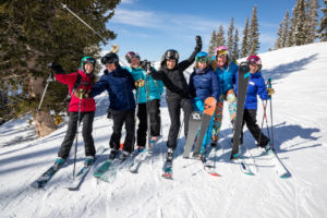 Group of women in skis on snowy hill laughing and hugging