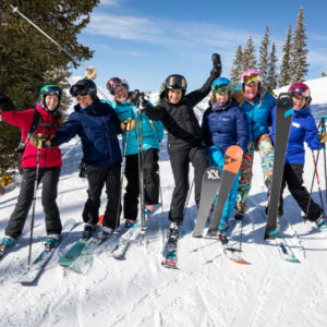 Group of women in skis on snowy hill laughing and hugging