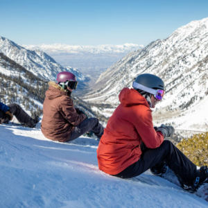 3 women snowboarders sitting on the side of a snowy mountain
