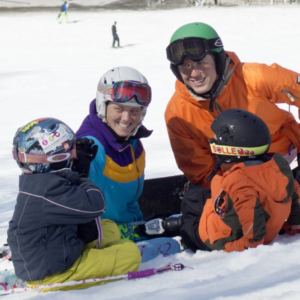 man and woman snowboarders sitting in snow with two kids