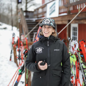Person in snow gear smiling and holding a walkie-talkie