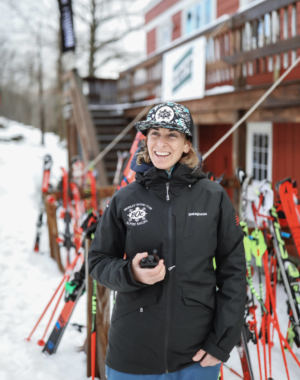 Person in snow gear smiling and holding a walkie-talkie