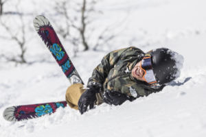 young kid laying in snow with skis on