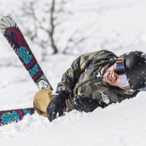 young kid laying in snow with skis on