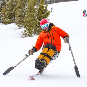 man in sit ski skiing down a snowy hill