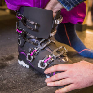 person fitting a ski boot on another person